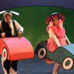 Al Kroeten and Miriam Gutierrez in Go Dog Go, dressed in dog costumes inside tiny cartoon cars