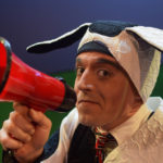 Al Kroeten in Go Dog Go, in a black and white dog costume, holding a bullhorn