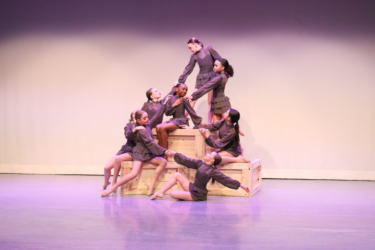 A group of dancers performing a routine on a stack of prop crates.