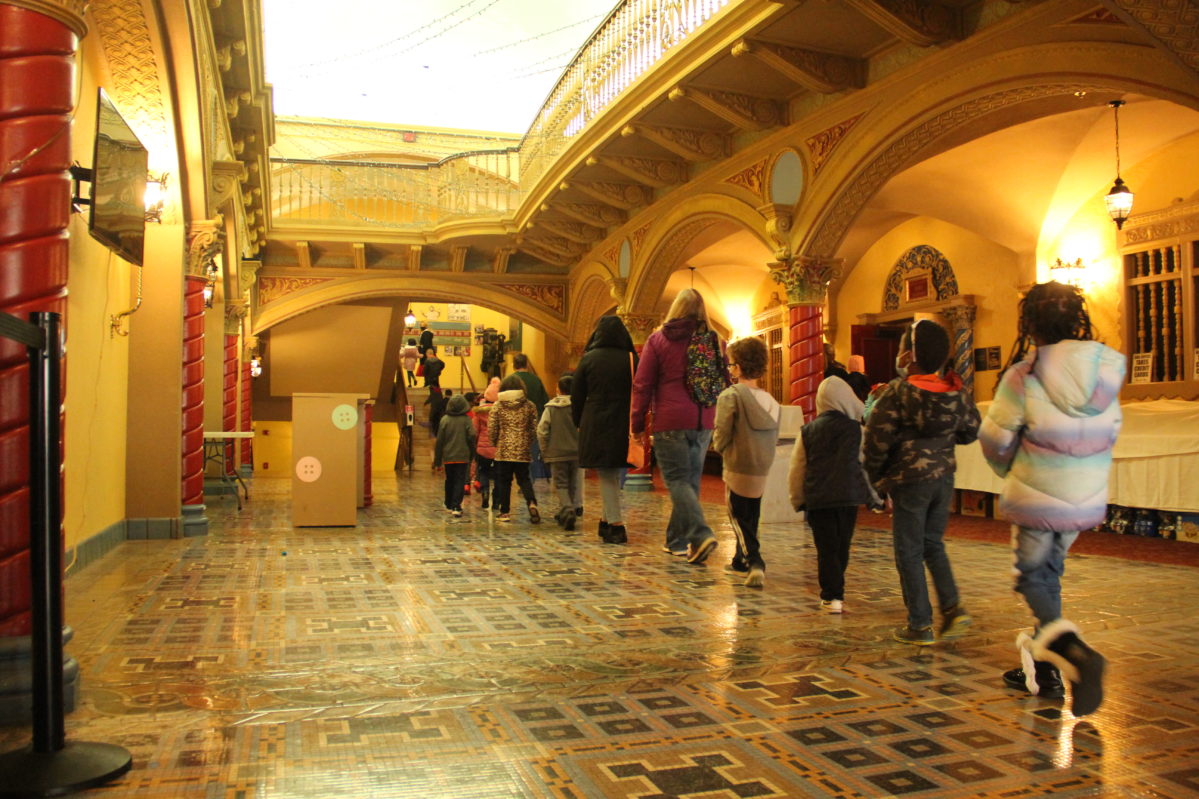 Young school students and chaperones walking into the Theater in a single file line.