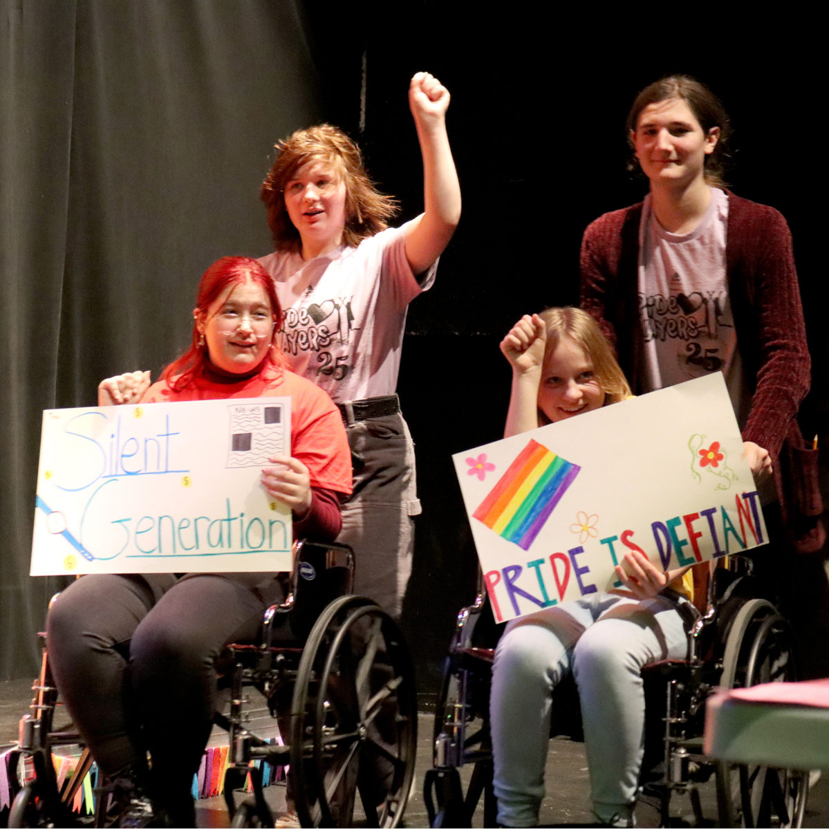 Teens performing in our Pride Players show. Two students are sitting in wheelchairs, while the other two stand behind in support.