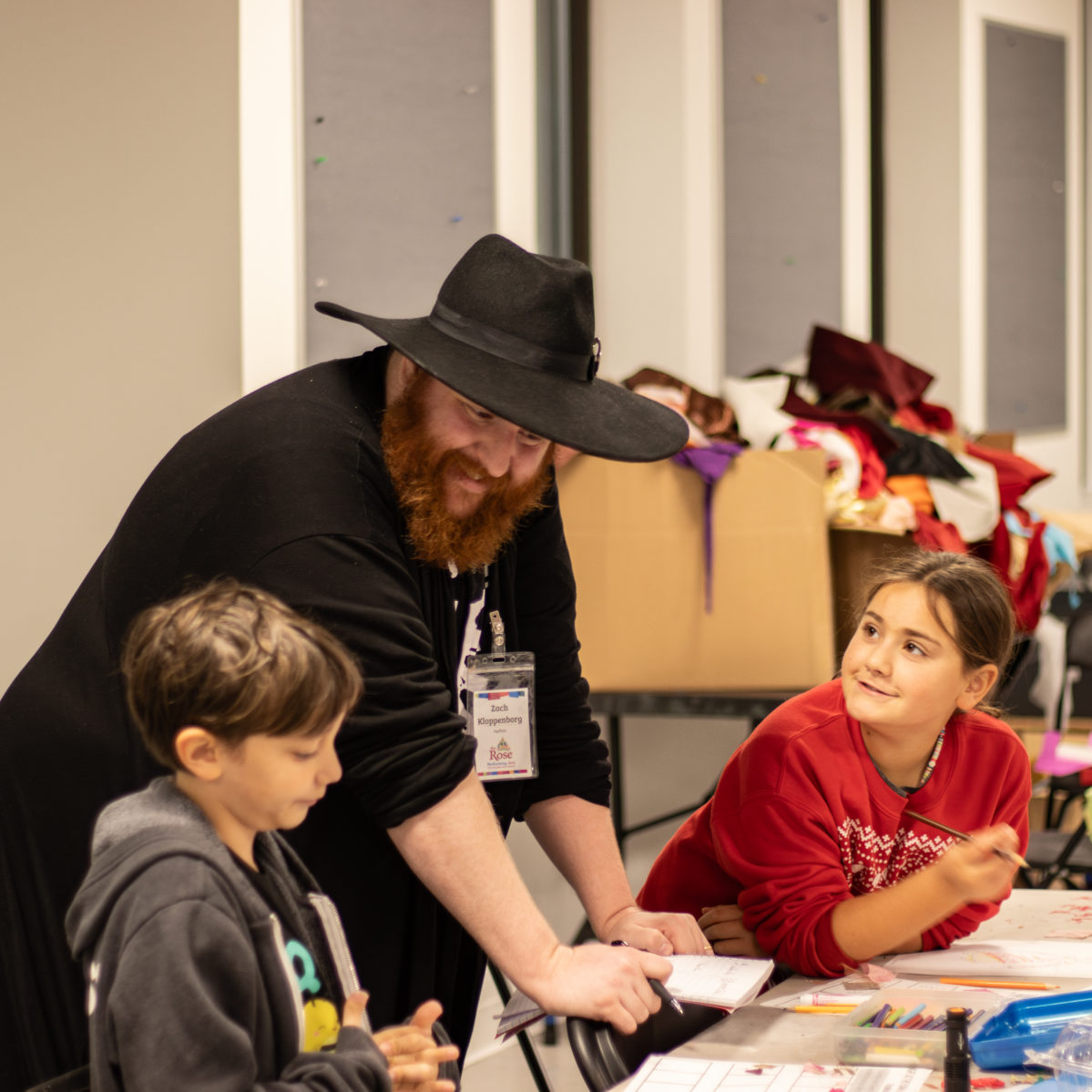 A Rose staff member working with two students in a classroom.